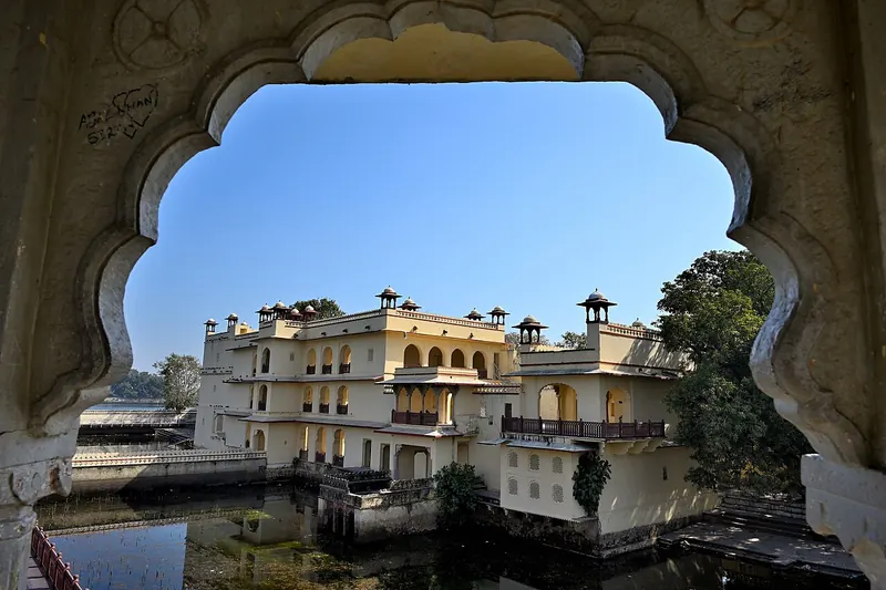 Abheda Mahal seen through a scalloped arch across the lake